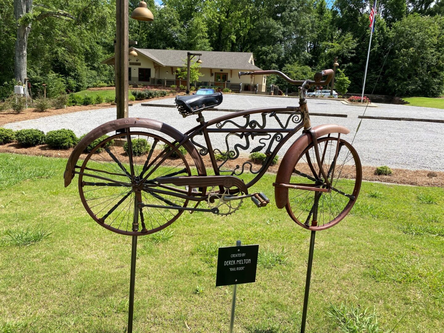 A bicycle sculpture is on display in the grass.