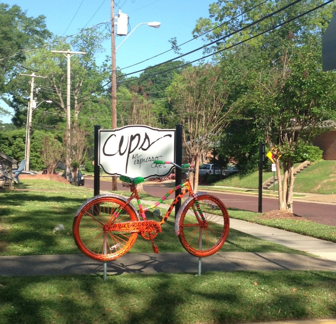 A bicycle is parked on the grass near a sign.