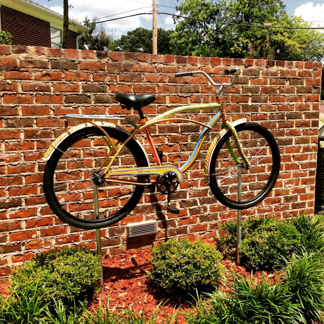 A bicycle is hanging on the wall of a brick building.